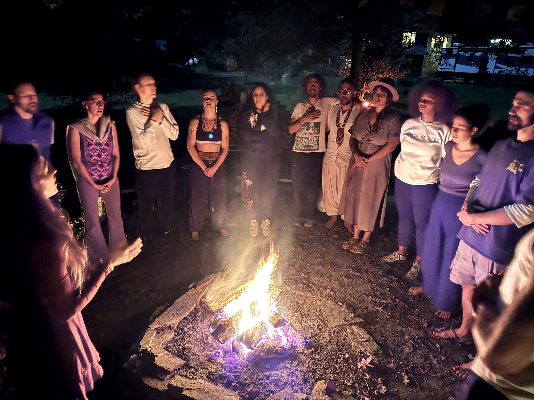 The Noble Movement community standing in a circle around a fire at night