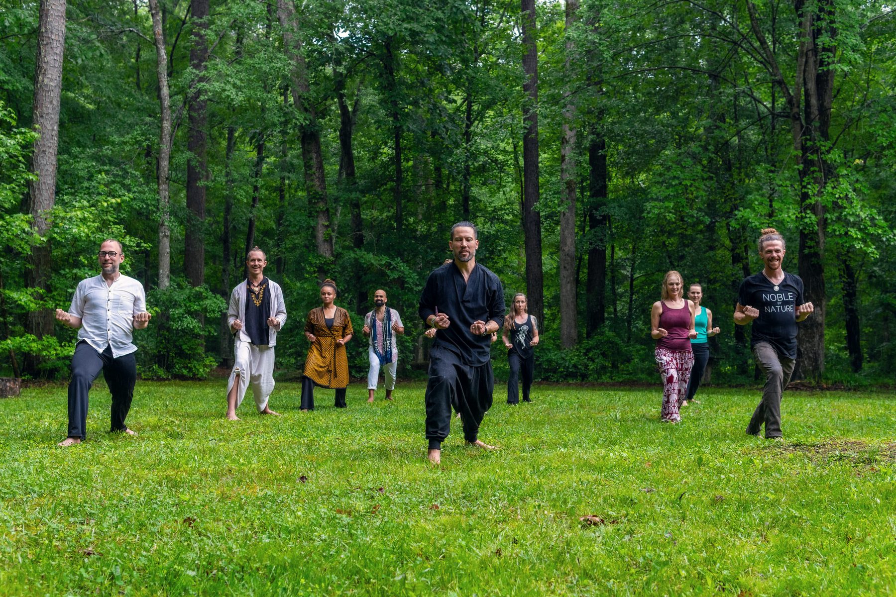 David walking toward the camera at the centre of the group, everyone facing forward, on a green field